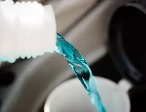 A bottle pours anti-freeze into a vehicle