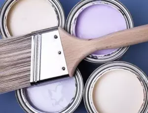 Cans of latex paint with a brush laying on top