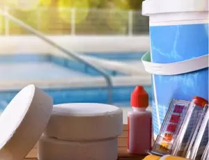 Pool chemicals with a backyard pool in the background