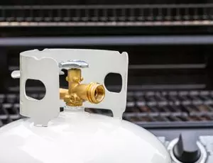 Propane tank in front of a backyard grill