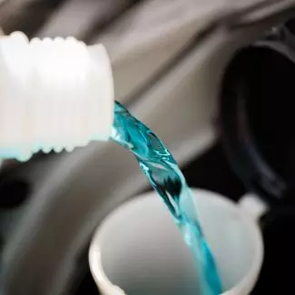 A bottle pours anti-freeze into a vehicle