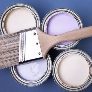 Cans of latex paint with a brush laying on top