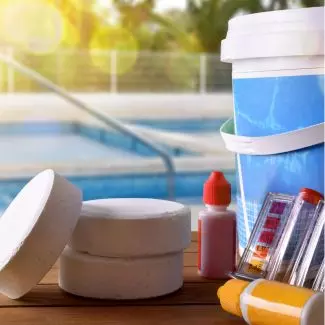 Pool chemicals with a backyard pool in the background