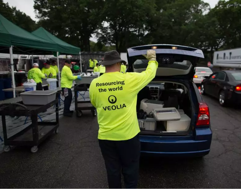 A Veolia employee empties household hazardous waste from a resident's vehicle trunk at a one-day HHW pickup event